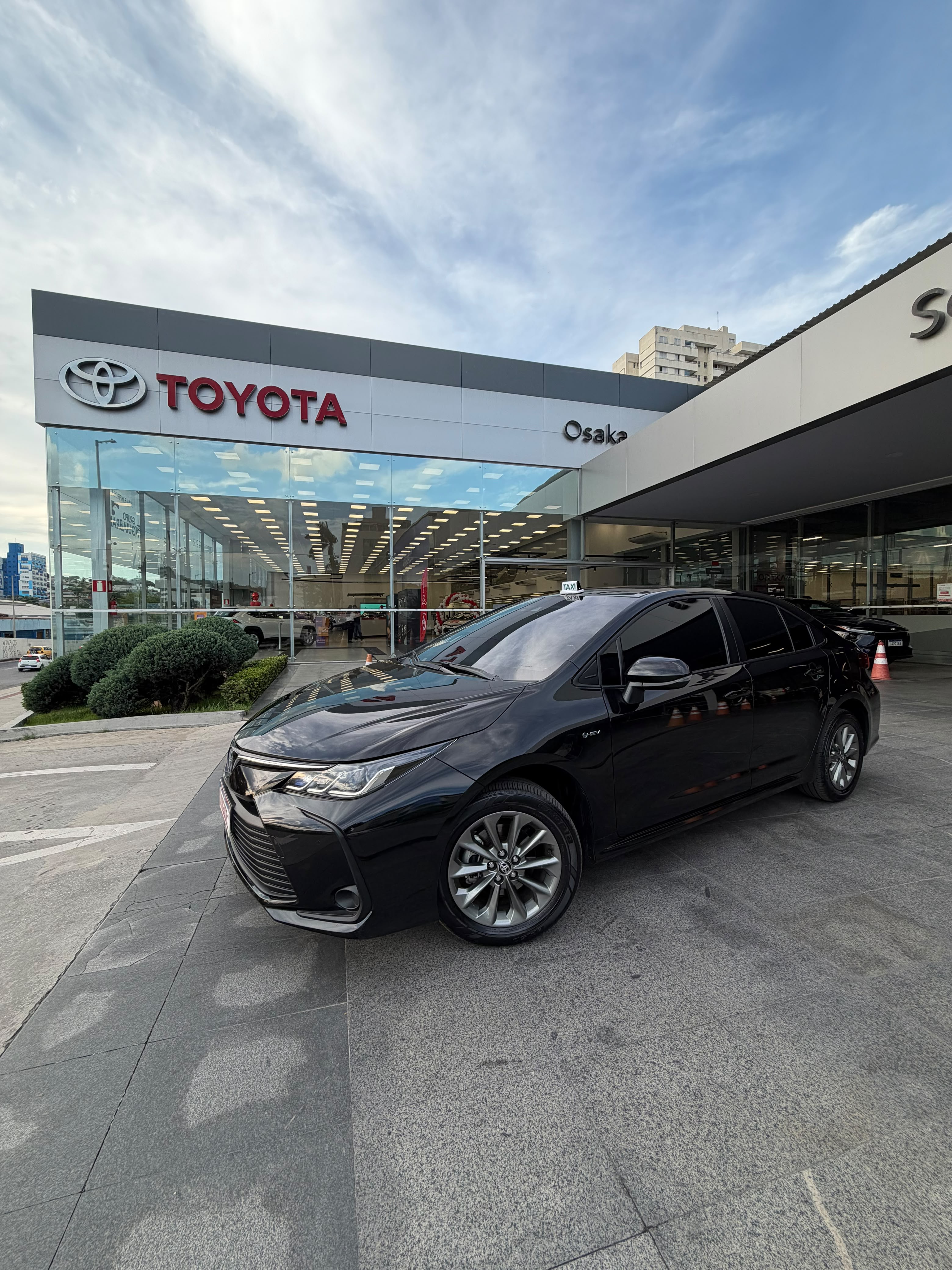 Sedan preto em frente a uma concessionária Toyota