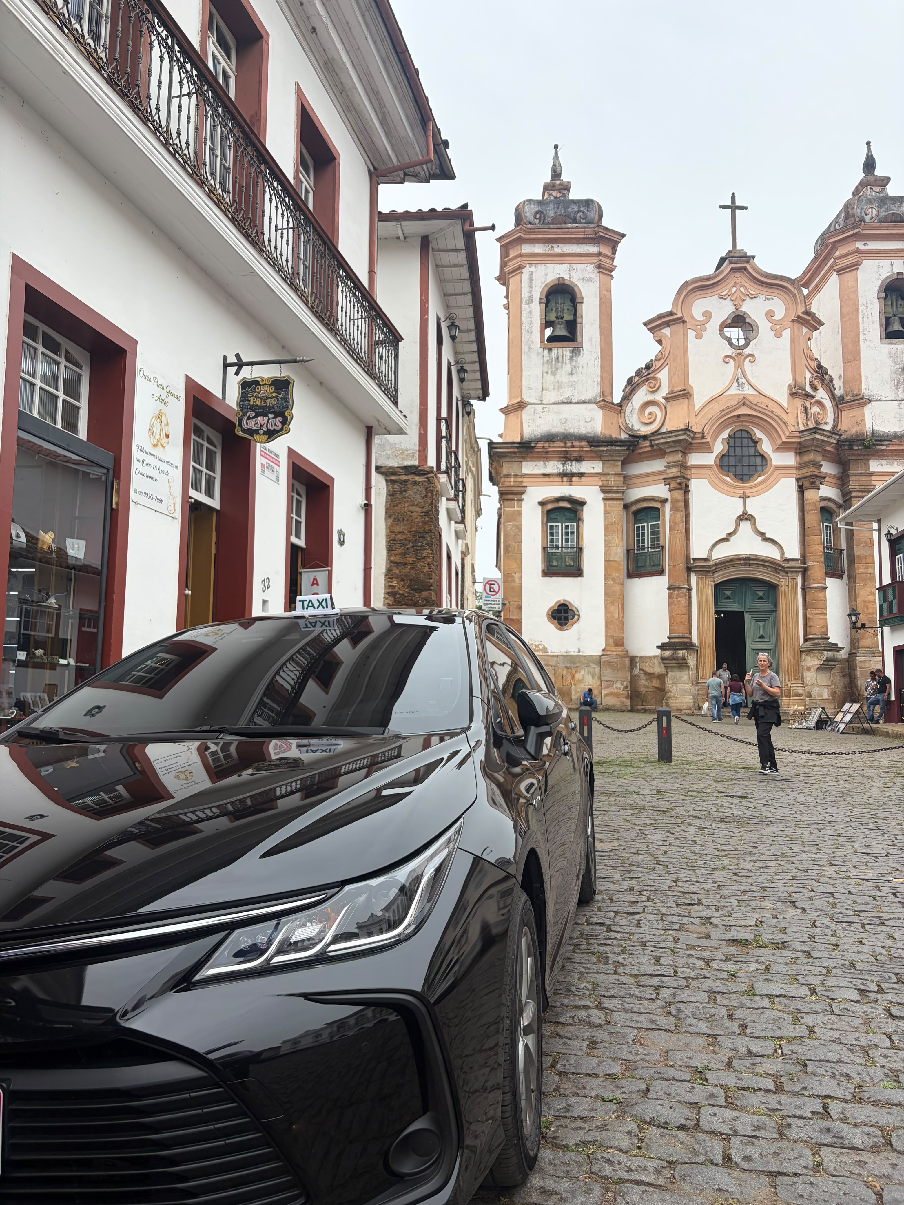 Sedan preto em rua de pedras ao lado de uma igreja histórica