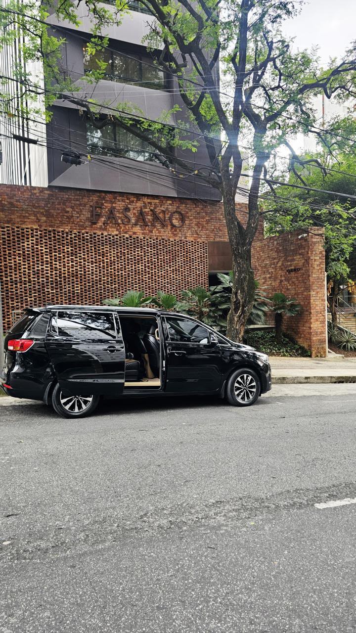Veículo executivo preto com a porta aberta ao lado de um muro de tijolos