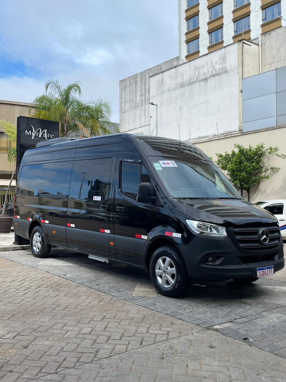 Van executiva preta Mercedes-Benz em frente a um hotel