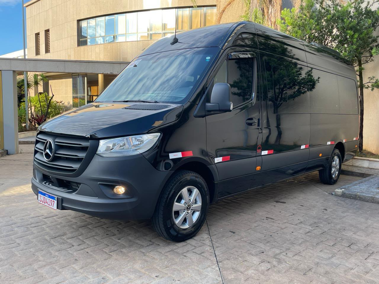 Van executiva preta Mercedes-Benz estacionada em frente a um hotel